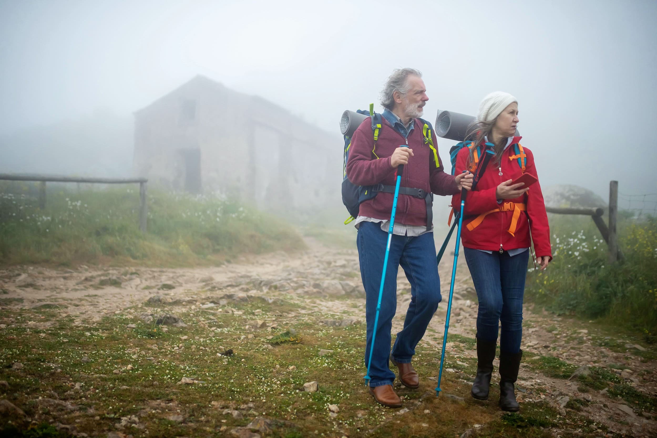 Senior hikers walking together on a foggy mountain path.